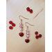 Light Pink Beaded Dangle Earrings with Small Red Heart Charm lays on a table surrounded by red beads. Gold plated fish hook ear wires. 